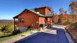 A log cabin with a porch, a stone foundation, and a view of the surrounding landscape. - Majestic View Lodge #426 (Sevierville)