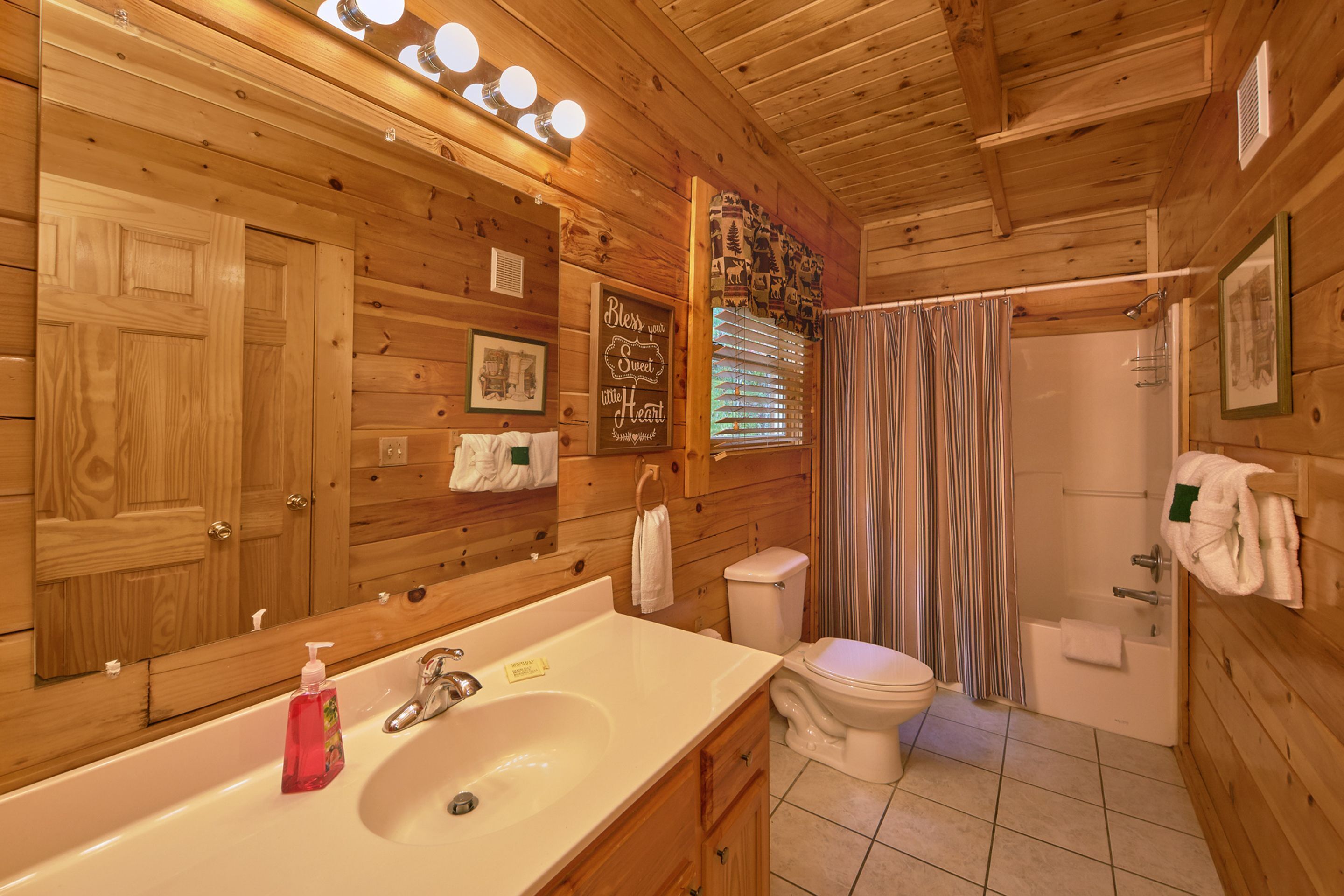 A wooden cabin bathroom with a sink, toilet, and shower.