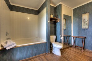 Een badkamer met een bad, toilet en een houten wastafelmeubel.