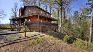 A log cabin with a porch and staircase, surrounded by trees. - Kickback Shack #298 (Sevierville)