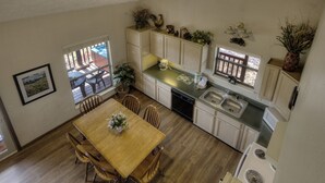 A compact kitchen with a wooden dining table, chairs, a dishwasher, and a stove. - Kickback Shack #298 (Sevierville)