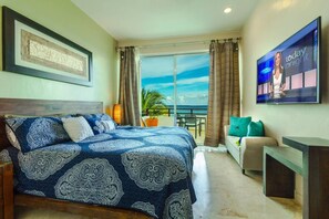 A bedroom with a large bed, a TV, a balcony with a view, and a desk. - Beachfront Penthouse! Private Jacuzzi! Live the Dream! (Playa del Carmen)
