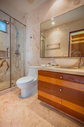 A modern bathroom with a glass-enclosed shower, a white toilet, and a wooden vanity with a large mirror. - Beachfront Penthouse! Private Jacuzzi! Live the Dream! (Playa del Carmen)