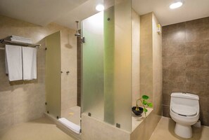 Une salle de bain moderne avec une douche à parois de verre, des toilettes et un lavabo agrémenté d’une plante.