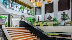 Un interior amplio con escalera de madera, techo de paja y diversas plantas.
