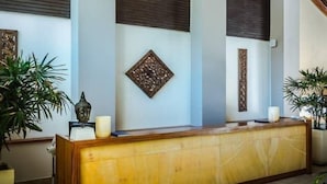 Un área de recepción con un mostrador de madera, lámparas colgantes tejidas y decoración mural.