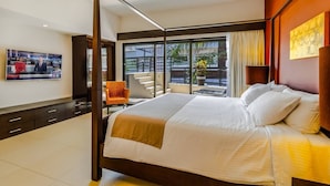 Habitación de hotel con una cama grande, televisor en la pared, una silla y un balcón con vistas.