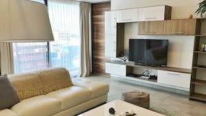 A modern living room with a sofa, coffee table, TV, and built-in shelving. - 3-br Condo, Partial Ocean View, 2blocks From Ocean (Playa del Carmen)
