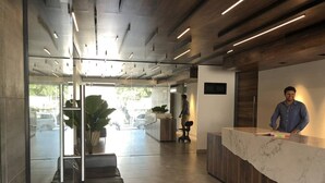 A modern reception area with a marble counter, seating area, and large windows. - 3-br Condo, Partial Ocean View, 2blocks From Ocean (Playa del Carmen)