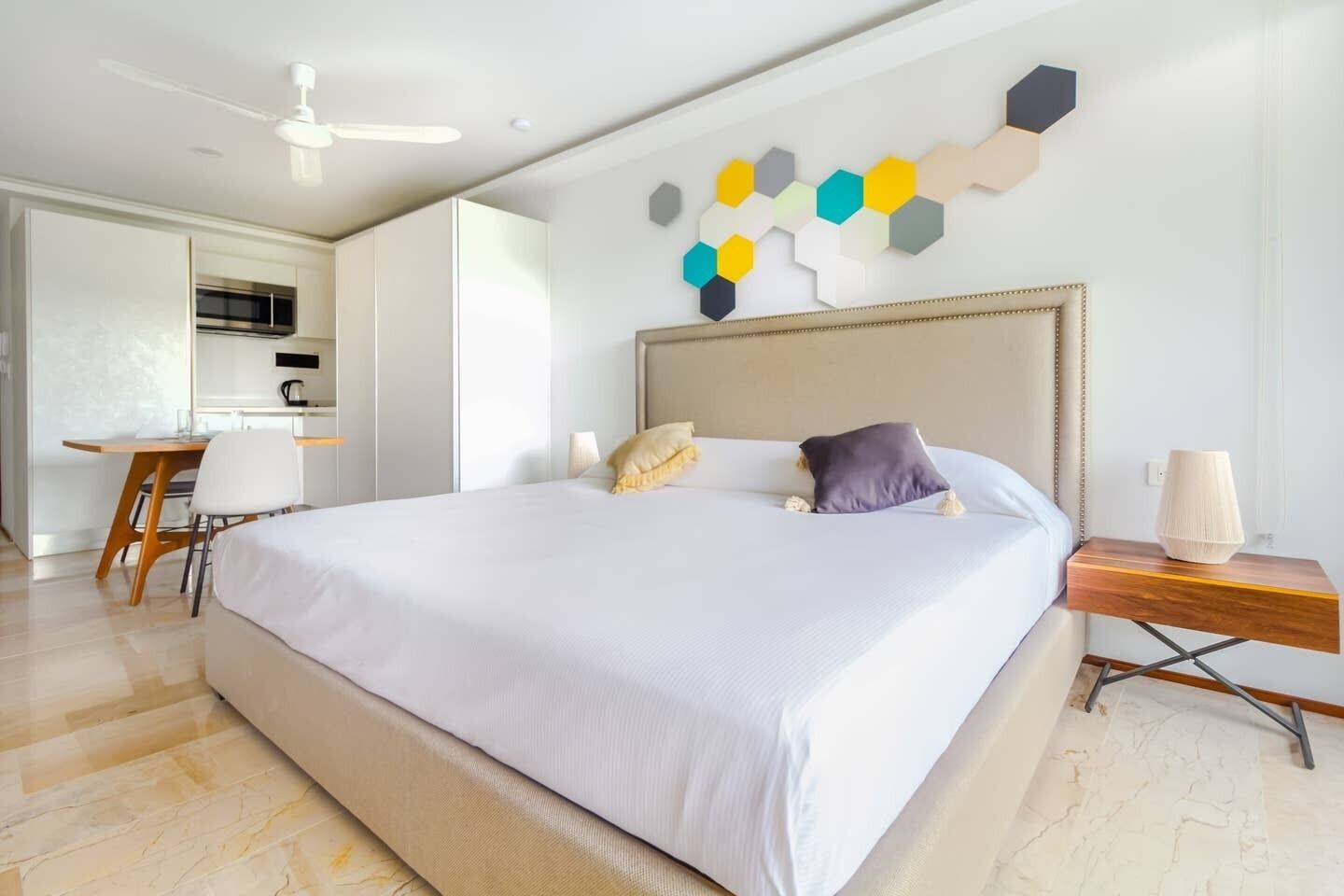 Une chambre d’hôtel moderne dotée d’un grand lit, d’un bureau et d’une kitchenette.
