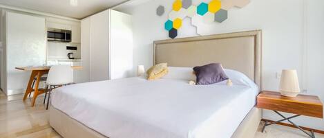 Une chambre d’hôtel moderne dotée d’un grand lit, d’un bureau et d’une kitchenette.