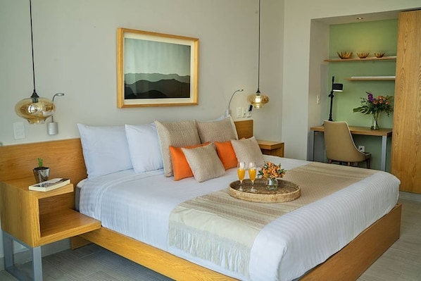 A modern bedroom with a large bed, bedside tables, a desk, and a chair.