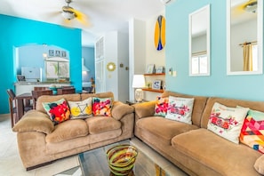 A living room with a sofa set, a dining area, and a kitchen.