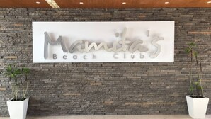 A sign for 'Mama's Beach Club' against a stone wall backdrop. - Dream Location! 2BR Near Beach+clubs!! Sleeps 6!! (Playa del Carmen)