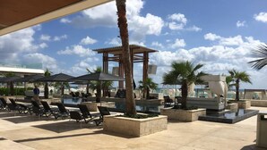 A resort pool area with lounge chairs, palm trees, and a gazebo. - Dream Location! 2BR Near Beach+clubs!! Sleeps 6!! (Playa del Carmen)