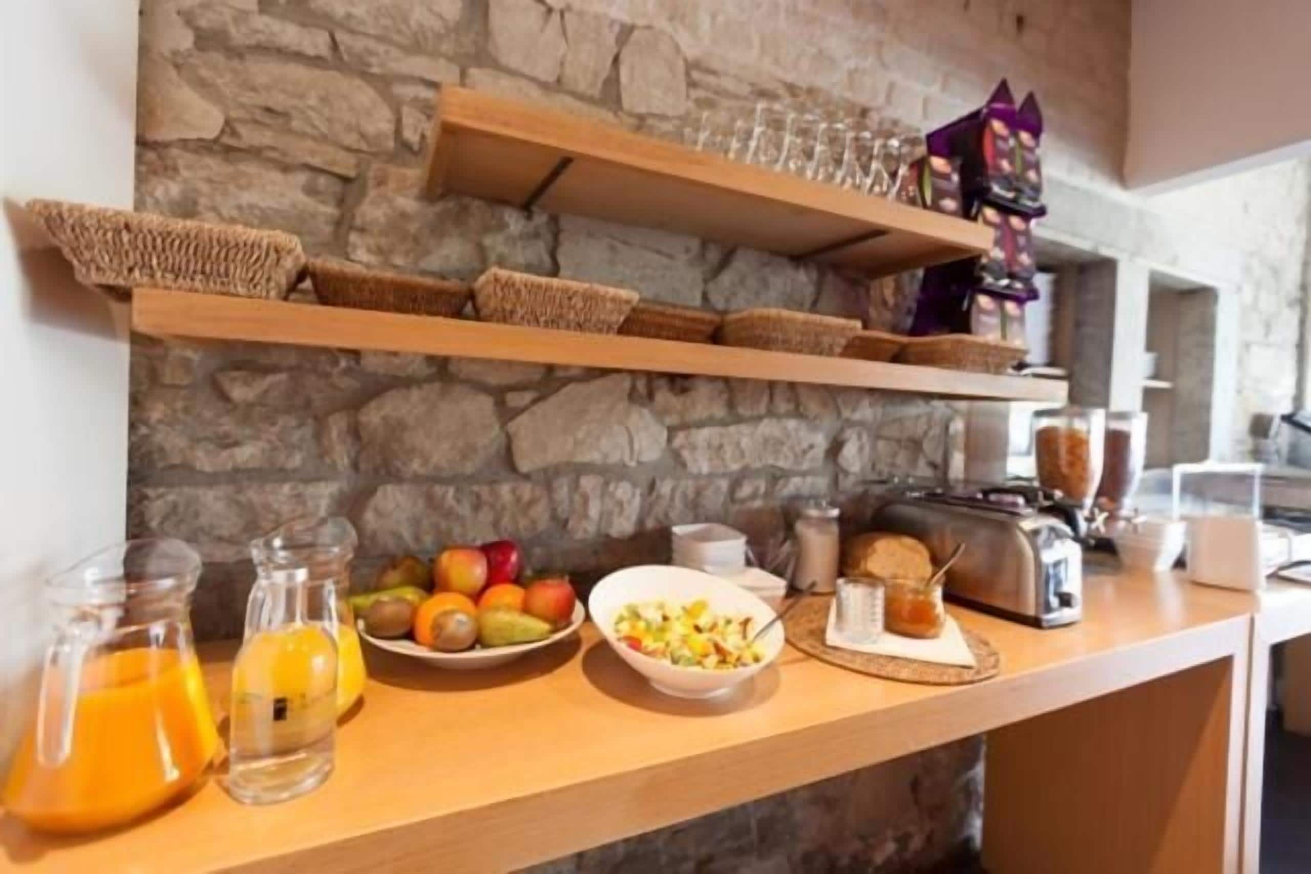 A breakfast bar with fruit, a toaster, and glass containers.