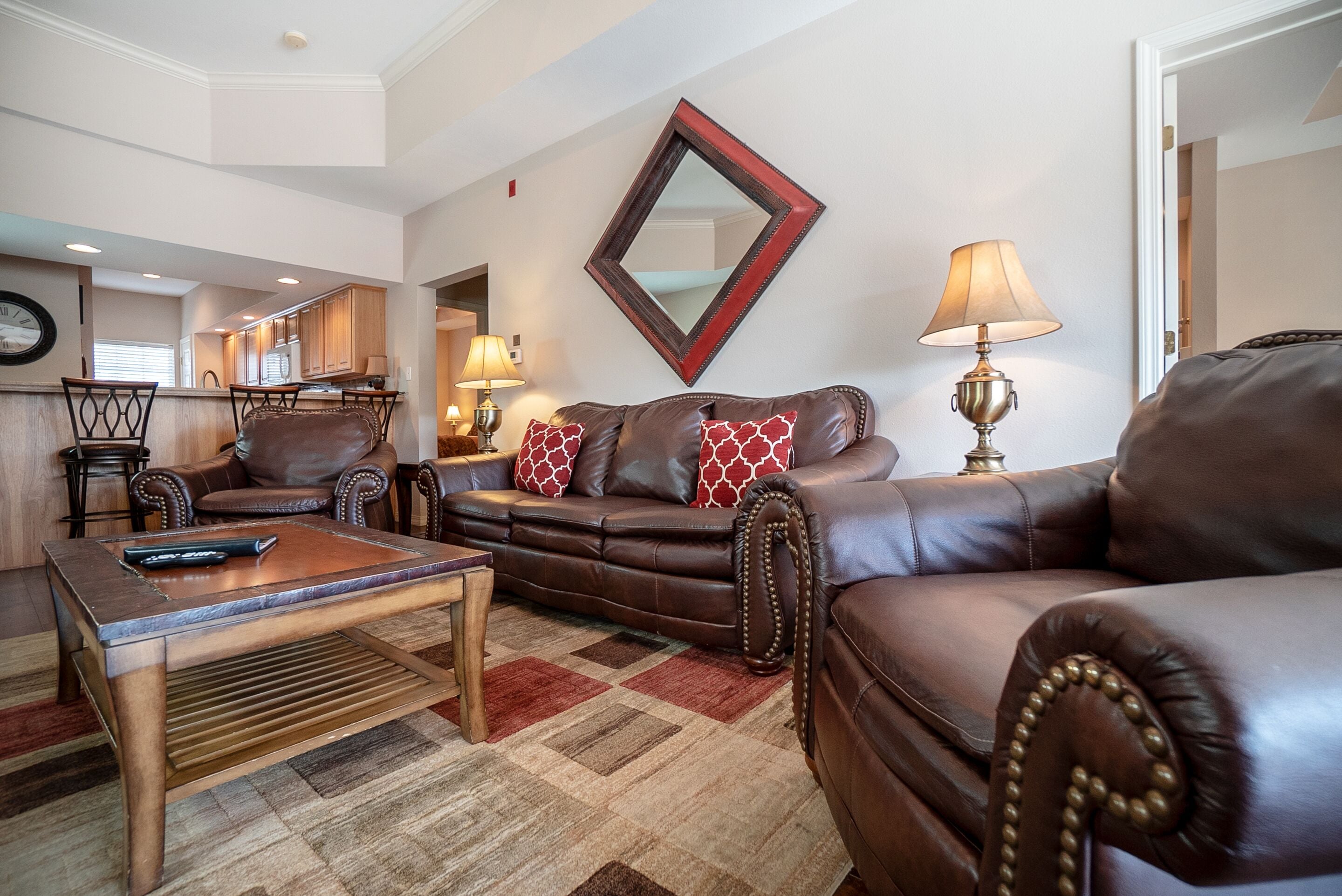 A living room with a brown leather sofa, a wooden coffee table, and a patterned rug.