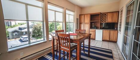 A spacious kitchen with large windows, wooden cabinets, and a dining area with a striped rug.