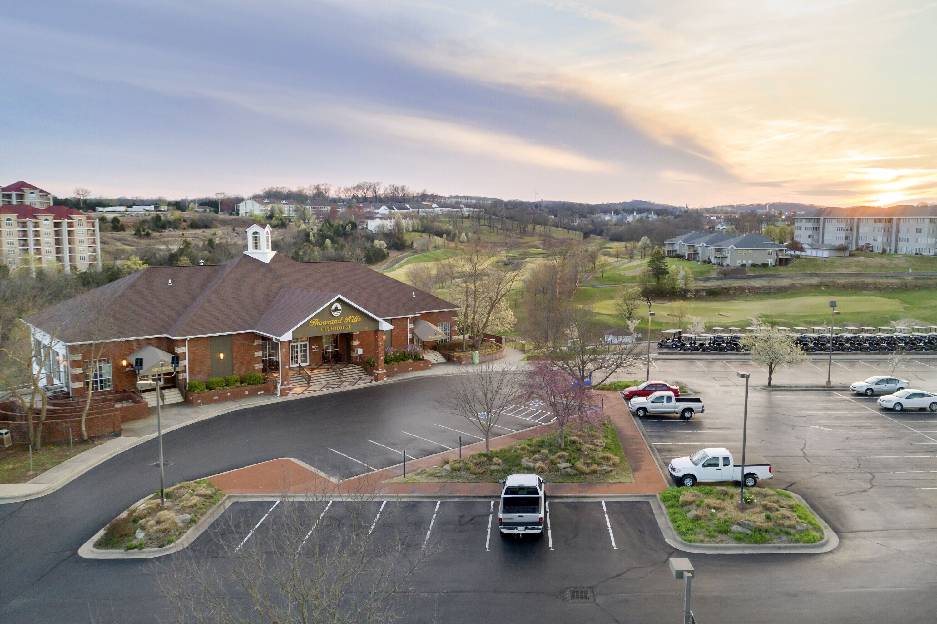 A parking lot with a building that has a red roof and a white entrance.