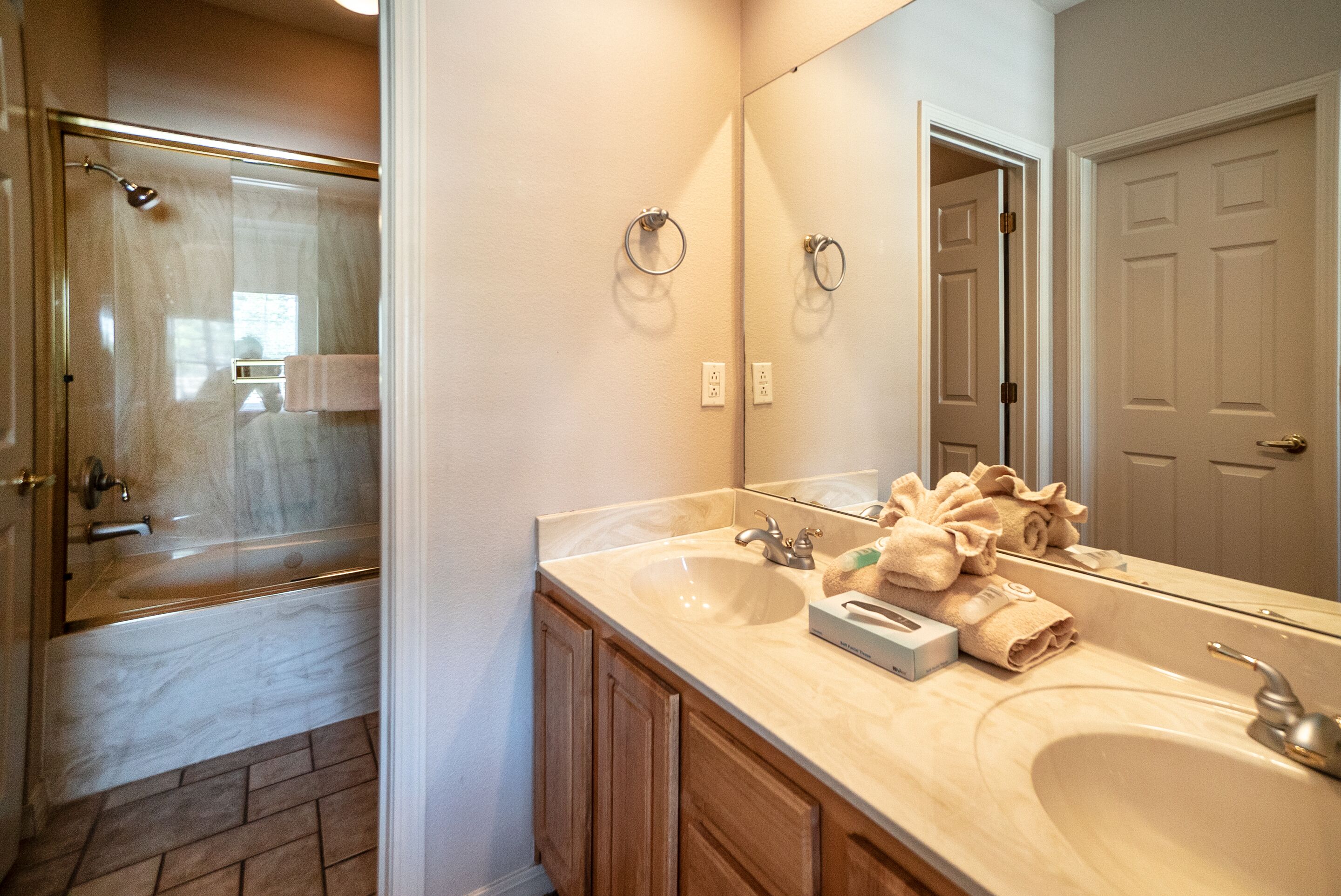 Une salle de bain avec un grand miroir, un lavabo et un espace douche.