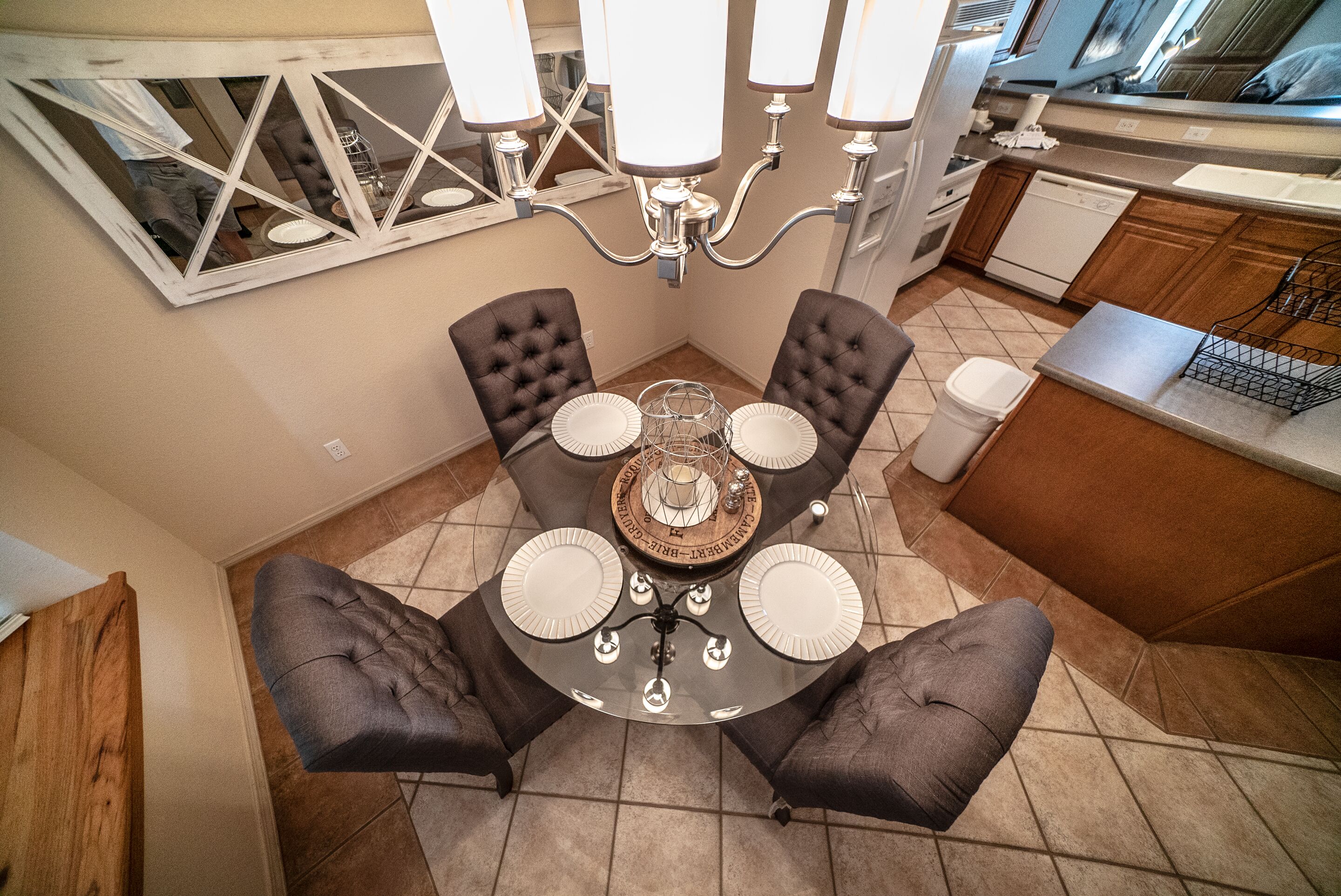 A dining area with a round table, four chairs, and a chandelier.
