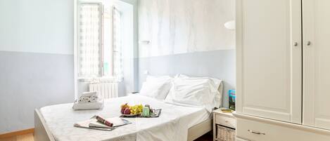 A bedroom with a bed, a wardrobe, a nightstand, and a window with curtains.