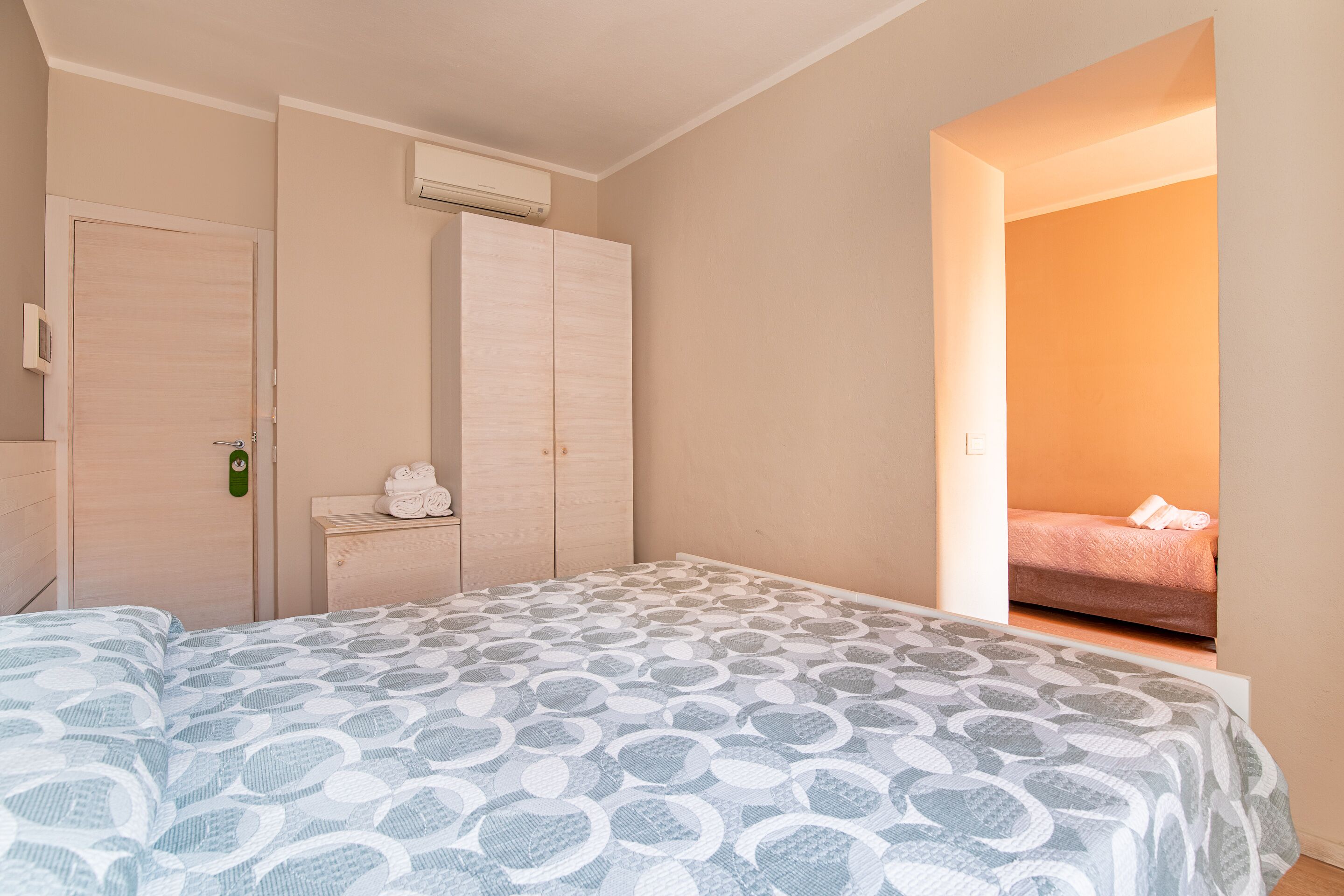 A bedroom with a bed, a wardrobe, and a small table with towels.