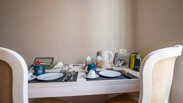 Une table mise pour le petit-déjeuner, avec de la vaisselle, des couverts, une bouilloire et une machine à café, préparée pour deux personnes.