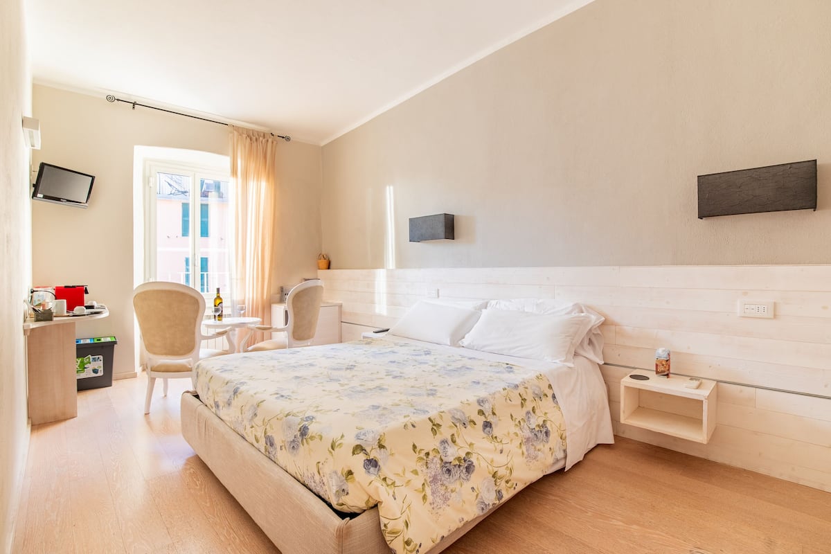 A hotel room with a bed, a desk, a chair, a TV, and a window.
