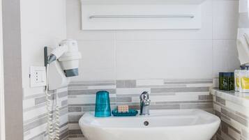 Une salle de bain avec un lavabo blanc, un sèche-cheveux et un miroir au-dessus.