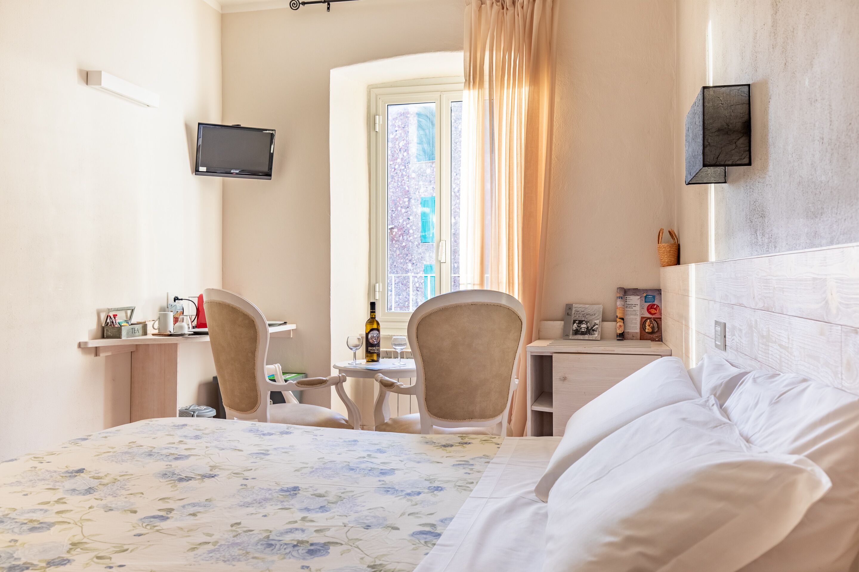A hotel room with a bed, a desk, a chair, a television, and a window with curtains.