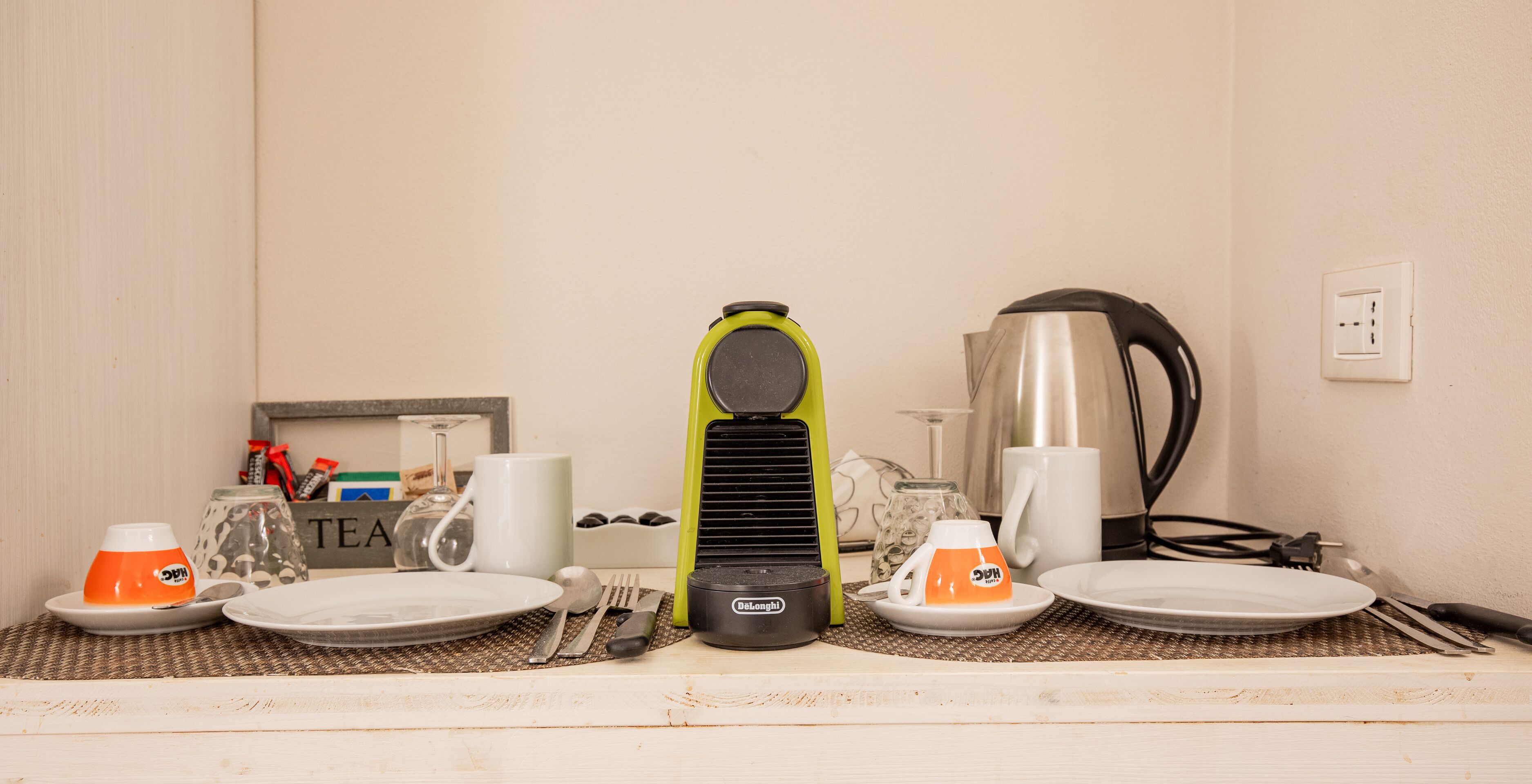 Eine Küchenarbeitsplatte mit Wasserkocher, Kaffeemaschine und einer Tasse.