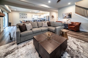 A spacious living room with a sectional sofa, a coffee table, and a staircase leading to an upper level. - Reunion Lodges at Thousand Hills (Branson)