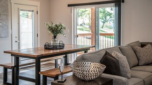 A modern living room with a wooden dining table, bench seating, and a sofa with patterned cushions. - Reunion Lodges at Thousand Hills (Branson)
