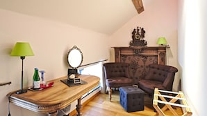 A room with a wooden table, two chairs, a small ottoman, a mirror, and a wooden cabinet with a clock. - Hotel Le Saint Hadelin (Houyet)