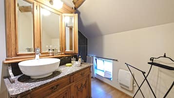 A bathroom with a wooden vanity, a large mirror, and a window with a view.