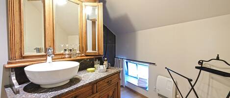 Un baño con tocador de madera, un espejo grande y ventana con vistas.