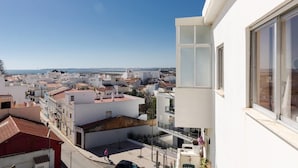 A residential area with white buildings, a clear sky, and a view of the sea. - Remarkable 2-Bed Apartment (ALVOR, Algarve)