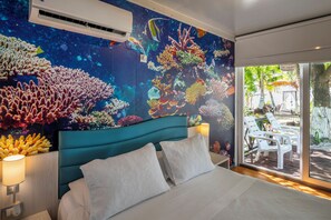 A bedroom with a large bed, a teal headboard, and a mural of colorful coral reefs. - Hotel Reina del Mar By Dorado (San Andrés)