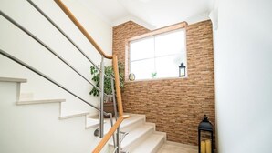 A staircase with white steps and wooden handrails, leading to a room with a brick wall and a window. - Laguna Formosa - Holidays in the Algarve (Faro)