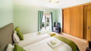A hotel room with two beds, a TV, a wardrobe, and a balcony with curtains. - Laguna Formosa - Holidays in the Algarve (Faro)