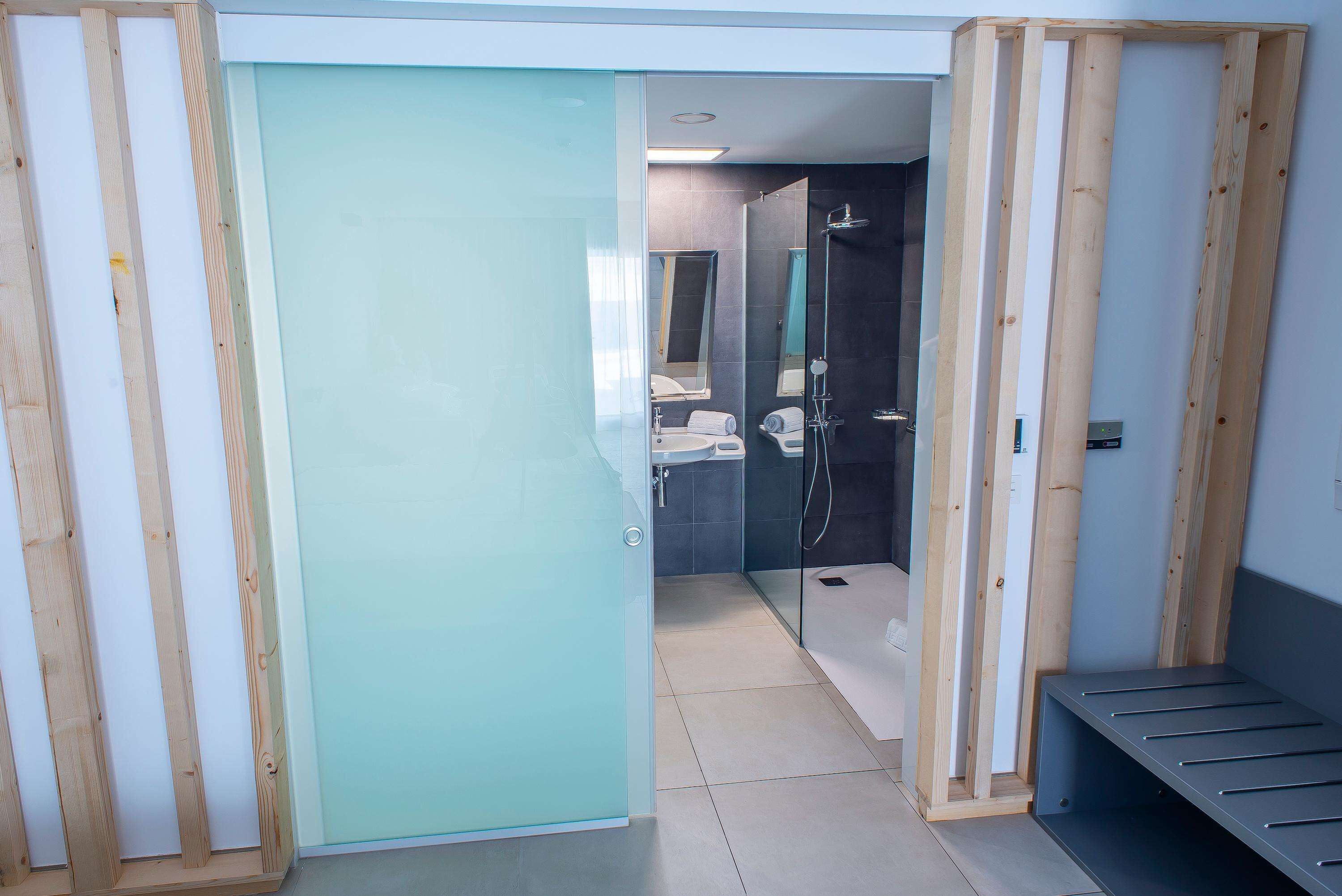 A modern bathroom with a glass shower enclosure, a sink, and a mirror.