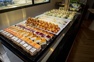 Un bufé con diferentes opciones de comida, incluyendo pasteles, sándwiches y ensaladas.
