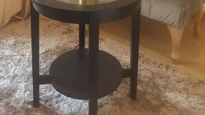 A round glass table with a plant, a sofa, and a wall-mounted painting of a tram.