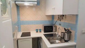 A compact kitchen with a microwave, sink, and a dishwasher.