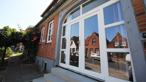 A red brick building with large windows and a sign that reads "Ausfahrt frei halten!"