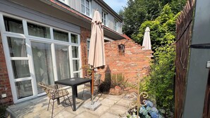A patio with a table and chairs, a brick wall, and a garden with hydrangeas.