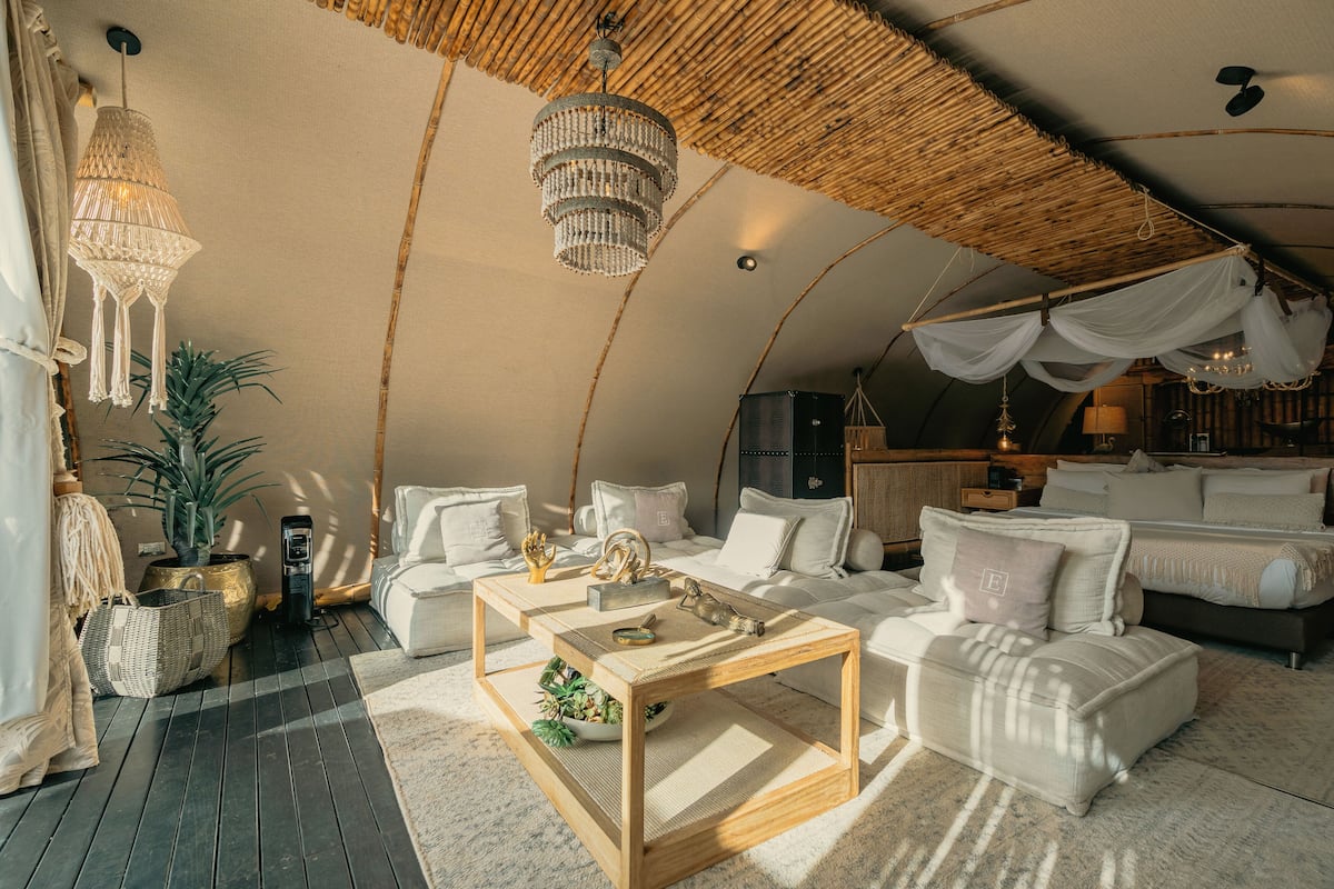 A cozy, well-lit tent-style room with a bed, a sofa, and a coffee table.