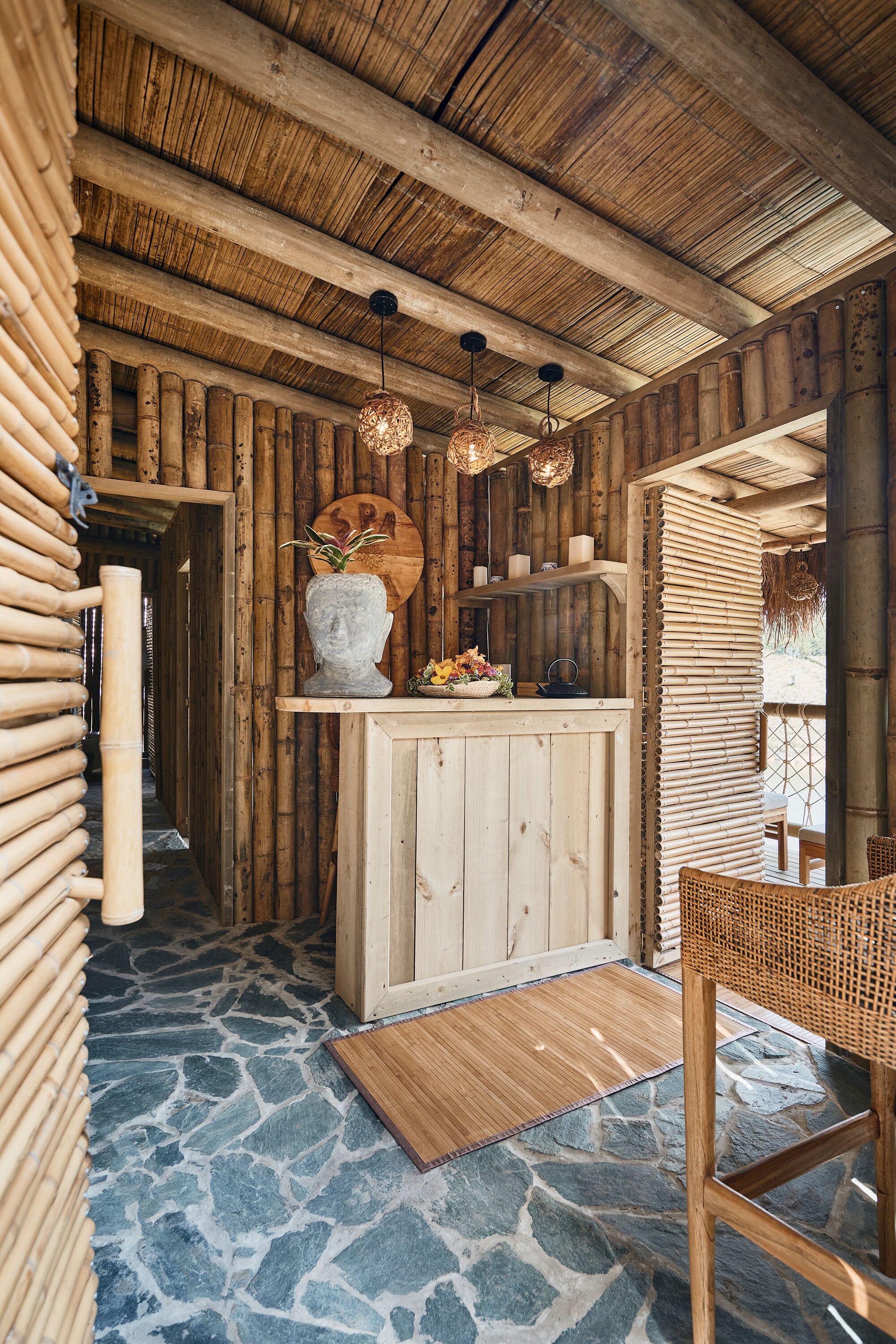 A wooden interior with a stone floor, a reception desk, and hanging lights.