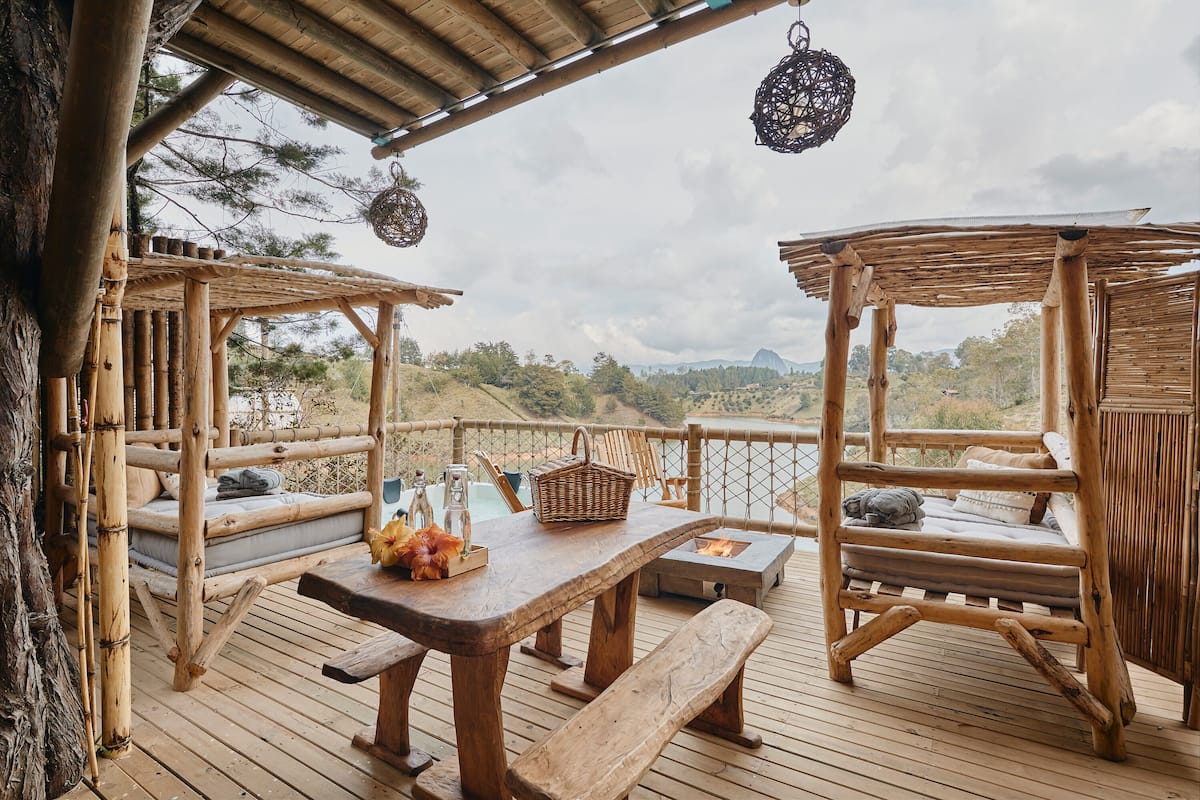 A wooden deck with a table, benches, and a fire pit.